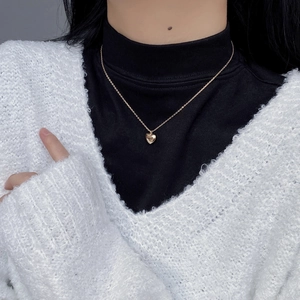Detail of minimalist gold heart pendant with fine engraving on a delicate chain