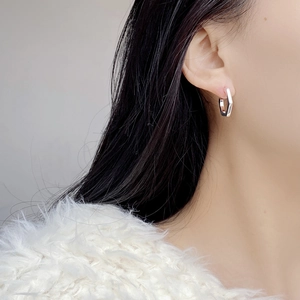 Close-up of S925 sterling silver hexagonal hoop earring worn by a model in soft lighting