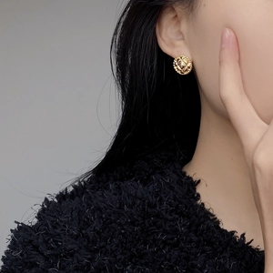 Close-up of vintage gold round stud earrings with embossed diamond pattern and bead edge