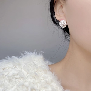 Macro detail of silver round stud earrings featuring a quilted pattern on a female model