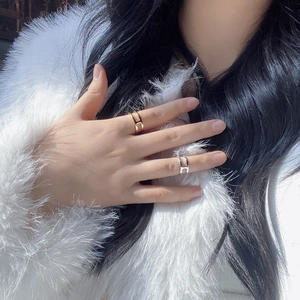 Dettaglio di anelli minimalisti color oro e argento a forma di H su una mano