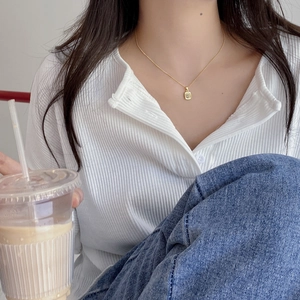 Gold rectangular pendant necklace with white diamond worn by a model in casual style