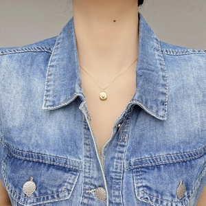 Golden S925 silver necklace with heart pendant on model wearing blue denim vest