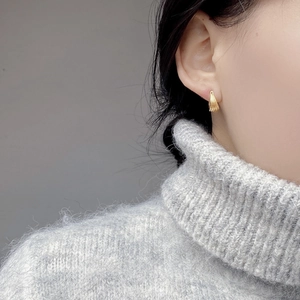 Close-up of minimalist gold-plated hoop earrings with vertical ribbed texture on ear