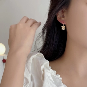 Elegant gold bow earrings with pearl drops worn by a model in a minimalist style