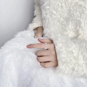 Close-up of S925 sterling silver hollow lace flower ring on soft white fabric background