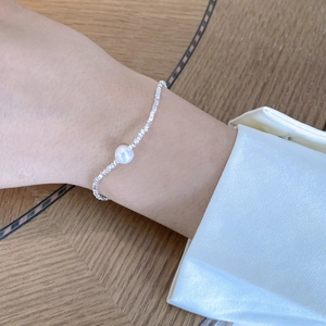 Detail of vintage S925 silver beaded bracelet with natural baroque pearl on woman's wrist