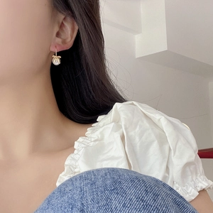 Close-up of S925 silver bow earrings with shell pearls worn by a model in soft light