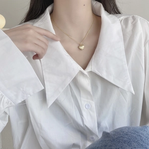 Elegant gold heart pendant necklace with a brushed metal finish worn by a female model