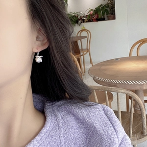 Elegant S925 silver bow earrings with shell pearl worn by a model in a purple jacket