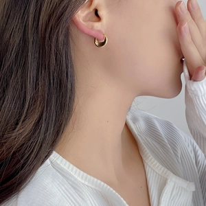 Minimalist S925 sterling silver golden hoop earrings worn by a model in warm light