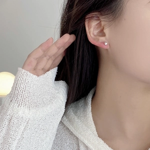 Close-up of minimalist S925 sterling silver ball stud earrings on a female model