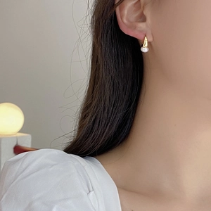 Close-up of S925 silver gold pearl hoop earring worn by a model in warm light