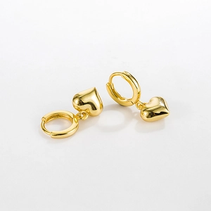 Macro shot of 925 silver golden heart earrings with polished finish on white background