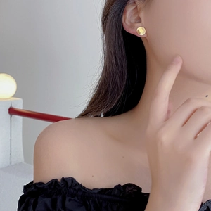 Minimalist gold round brushed silver stud earrings worn by a model in a warm setting
