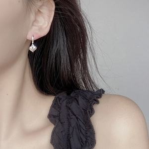 Close-up of 925 sterling silver heart charm hoop earring worn on female ear