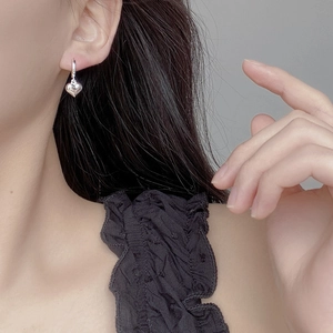 Minimalist 925 sterling silver heart hoop earrings worn on a female model