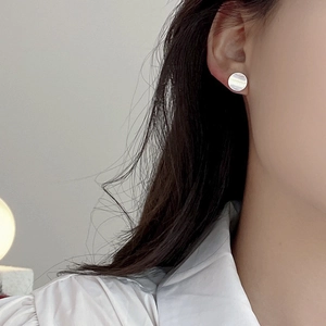 Detail of round S925 silver stud earring with brushed pearl texture on female model