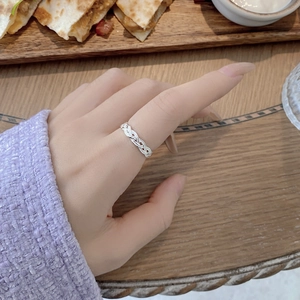 Detail shot of a silver woven textured ring with an open adjustable design on index finger
