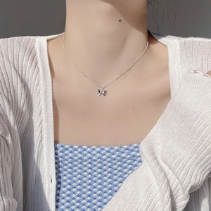 Minimalist 925 sterling silver bow pendant necklace worn on a woman's collarbone