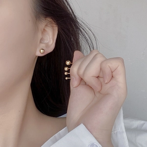 Set of minimalist gold ball stud earrings in four different sizes shown on a model