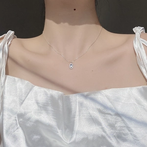 Detail of S925 silver necklace with oval light blue gemstone on model's neck