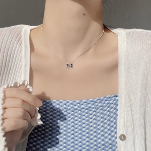 Close-up of S925 sterling silver bow pendant necklace worn on a female collarbone