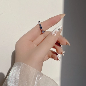 Detail showing hand wearing silver ring with blue heart zircon stones and geometric shadows