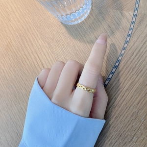 Close-up of a delicate gold woven texture ring worn on finger in a lifestyle setting