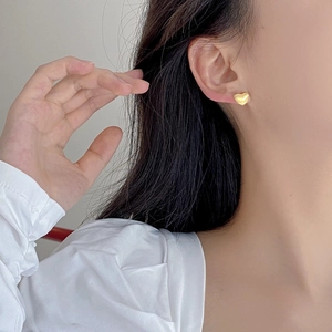 Gros plan de boucles d'oreilles cœur évidé en argent S925 doré mat portées par un mannequin