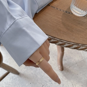 Detail of woven 925 silver ring featuring intricate interlaced golden metal textures