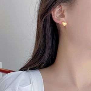 Boucles d'oreilles cœur en argent S925 avec finition or brossé portées sur modèle