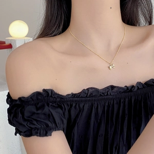 Detail of a gold 925 silver bow pendant necklace worn by a model on a black outfit