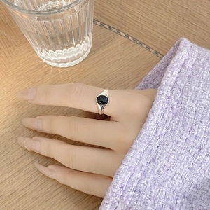 Close-up of a silver ring with an oval black onyx stone on a woman's finger