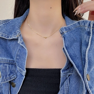 Detail of 18K gold bead necklace on model highlighting minimalist spherical design
