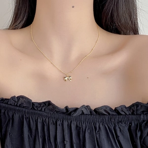 Elegant 925 sterling silver bow pendant necklace with gold finish on model collarbone
