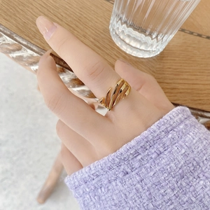 Close-up of a gold geometric cutout ring worn by a model against a soft purple sleeve