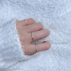 Dettaglio di anelli in argento sterling a trama irregolare su sfondo morbido e neutro