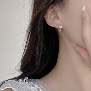 Macro shot of silver S925 heart twist hoop earrings with sparkling zircon on earlobe