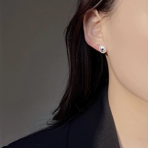 Detail of vintage silver oval stud earring with blue stone inlay and milgrain edge on ear