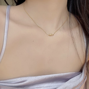 Detailed view of a gold barbed wire pendant necklace on a purple satin top model