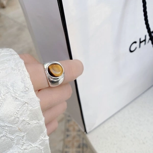 Primer plano de un anillo de plata de ley 925 con piedra de ojo de tigre en la mano