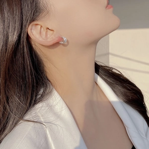 Close-up of S925 sterling silver C-shaped hoop earrings with spiral woven texture on model