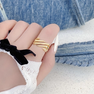 Close-up of a gold geometric open ring with layered architectural lines worn on a finger