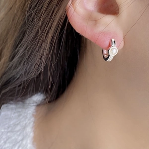 Détail de boucles d'oreilles créoles en argent sterling avec perle baroque sur modèle