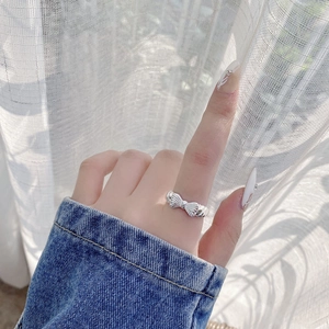 Adjustable S925 sterling silver bow ring with textured metallic finish on model hand