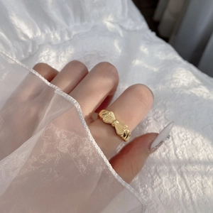 Elegant gold bow ring with textured finish on white lace background for a feminine look