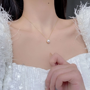 Gros plan d'un pendentif en perle d'eau douce blanche sur une chaîne en or élégante