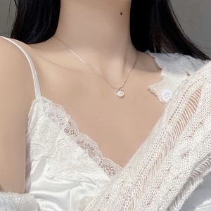 Close-up of S925 silver necklace with white shell pendant on a model neck