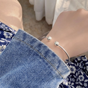 Close-up of minimalist 925 silver open bangle featuring two spherical beads on a wrist